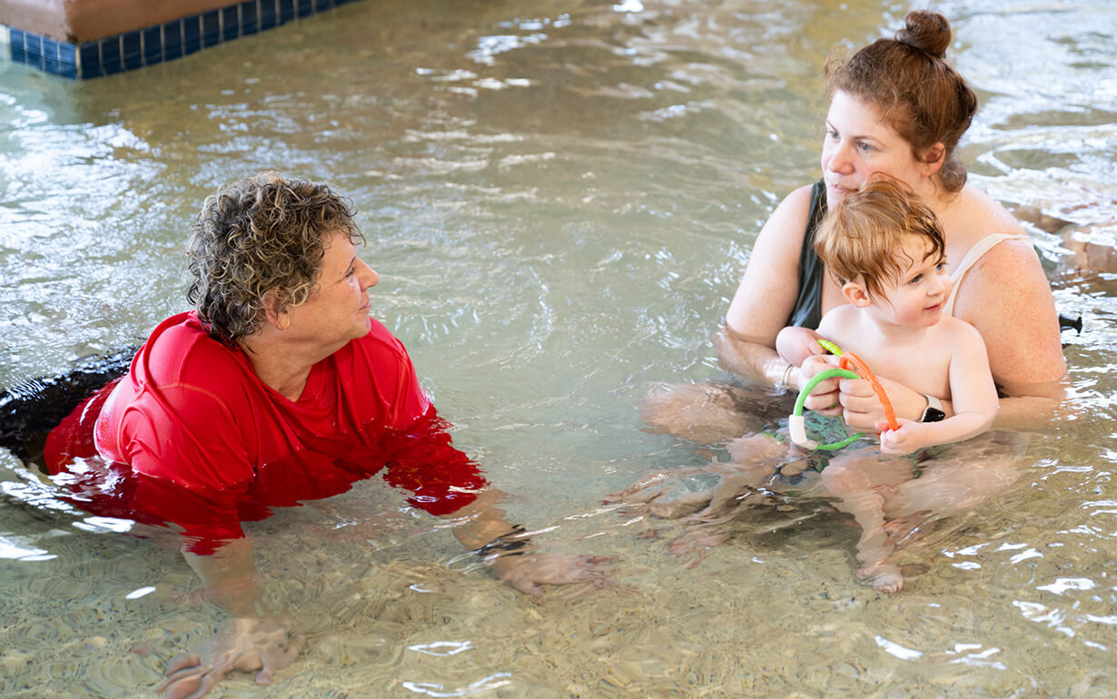 trainer, mom and child swimming